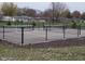 View of the community tennis courts with black chain link fence, nets, and dark soil landscaping at 1704 N Winthrop Rd, Muncie, IN 47304
