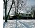 Inviting two-story home with a stone facade and shuttered windows, surrounded by mature trees in a snow covered lawn at 296 Ironwood Ct, Carmel, IN 46033