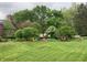 Well-manicured front yard with mature trees, flowering shrubs, and lush green grass at 3370 Walnut Creek Ct, Carmel, IN 46032