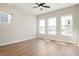 Bright bedroom featuring hardwood floors, neutral walls, three windows, and a modern ceiling fan at 555 Gilder Dr, Carmel, IN 46032