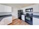 Well-lit kitchen featuring modern black appliances, white cabinets, and wood-look flooring at 6608 Rushing, Noblesville, IN 46062