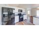 Open kitchen with black appliances and wood-look flooring flowing into adjacent living space at 6608 Rushing, Noblesville, IN 46062