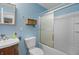 This bathroom features a shower-tub combo, a wooden vanity, and blue walls at 7610 Brehob Rd, Indianapolis, IN 46217