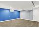 A spacious basement features carpeted flooring, blue accent wall, and neutral gray walls at 118 S 11Th Ave, Beech Grove, IN 46107