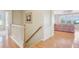 Bright hallway featuring hardwood floors, white railings, and a glimpse of the living room at 12880 Oxbridge Pl, Fishers, IN 46037