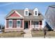 Charming two-story red home with inviting front porch and manicured lawn on a sunny day at 12964 Walbeck Dr, Fishers, IN 46037