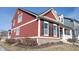 Two-story red home with white trim, black shutters and a brick foundation at 12964 Walbeck Dr, Fishers, IN 46037