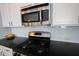 A modern kitchen featuring stainless steel appliances, including a microwave and range, with a sleek black countertop at 12964 Walbeck Dr, Fishers, IN 46037
