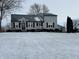 Charming two-story home features a metal roof, black shutters, covered porch, and winter landscaping at 1905 Apple St, Greenfield, IN 46140