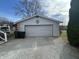 Exterior view of detached garage with gray siding and overhead door, adjacent to a gravel driveway at 1905 Apple St, Greenfield, IN 46140