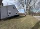 Side exterior of home with mature trees and gravel driveway at 1905 Apple St, Greenfield, IN 46140