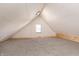 Unfinished attic featuring an A-frame roof, carpeted floors, and a small window at 2110 N Talbott St, Indianapolis, IN 46202