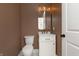 Elegant powder room featuring a white vanity with gold fixtures, a toilet, and dark brown walls at 2110 N Talbott St, Indianapolis, IN 46202