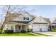 Inviting home featuring a two-car garage, front porch, manicured lawn, and charming architectural details at 3841 Constitution Dr, Carmel, IN 46032
