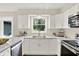 Well-lit kitchen with white cabinets, stainless steel appliances, quartz countertops and a view of the backyard at 502 Ironwood Dr, Carmel, IN 46033