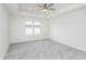 Bright bedroom with ceiling fan and tray ceiling; it features neutral walls, plush carpet, and a large window at 5874 Harbour Town Dr, Noblesville, IN 46062