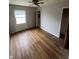 A bedroom with hardwood floors, a ceiling fan, and a large window providing natural light at 6533 Parker Ln, Indianapolis, IN 46220