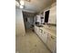 Shows an open kitchen design with white cabinets, a sink under the window, and vintage appliances. Needs TLC at 6533 Parker Ln, Indianapolis, IN 46220