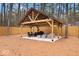 Outdoor pavilion in a wooded backyard, featuring a pitched roof, wood beams, and comfortable seating arrangement at 7643 Dean Rd, Indianapolis, IN 46240