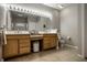 Bathroom with double sinks, wood cabinets, and a large mirror with Hollywood-style lighting at 10246 Eller Creek Dr, Fishers, IN 46038