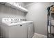 Functional laundry room with white washer and dryer, storage shelf, and tiled flooring at 10246 Eller Creek Dr, Fishers, IN 46038