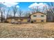 View of the backyard with yellow house, sliding glass doors, a patio, and bare trees at 1852 W 62Nd St, Indianapolis, IN 46260