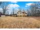 A spacious backyard with a yellow house with a brick foundation against a clear blue sky at 1852 W 62Nd St, Indianapolis, IN 46260