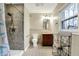 Bright bathroom features a walk-in shower with gray tile, a wooden vanity, and a window with natural light at 1852 W 62Nd St, Indianapolis, IN 46260