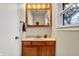 Bathroom vanity with wooden cabinets, cream counters, and a framed mirror with lighting at 1852 W 62Nd St, Indianapolis, IN 46260