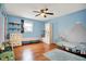 Bright bedroom featuring blue walls, hardwood floors, a ceiling fan, and mountain graphics at 1852 W 62Nd St, Indianapolis, IN 46260