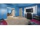 Living room with blue walls and gray carpet, showing a doorway to another room, a TV on a dresser and light from a window at 2610 Caroline Ave, Indianapolis, IN 46218