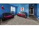 Vibrant blue living room featuring comfortable black sofas, soft carpeting, and bright natural light from the window at 2610 Caroline Ave, Indianapolis, IN 46218