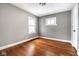 Cozy bedroom featuring hardwood floors, two windows, and neutral paint at 3708 Rockville Rd, Indianapolis, IN 46222