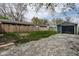 View of garage and back yard with mature trees and gravel parking area at 3708 Rockville Rd, Indianapolis, IN 46222