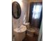 Modest bathroom featuring a white sink vanity, toilet, and window with curtains, offering a functional space at 732 W 12Th St, Indianapolis, IN 46202