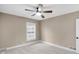 Neutral bedroom featuring a ceiling fan, a bright window with white trim, and plush carpeting at 7999 Englewood Rd, Indianapolis, IN 46240