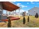 A spacious backyard has a covered wood porch, a playset and well-maintained grass at 9063 Moyer Pl, Pendleton, IN 46064