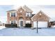 Charming two-story brick home featuring an attached two-car garage and a snow-covered front yard at 9239 Stones Ferry Way, Indianapolis, IN 46278