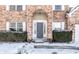 Close-up of a brick home's arched entrance featuring a grey front door and manicured bushes in winter at 9239 Stones Ferry Way, Indianapolis, IN 46278