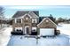Two story brick home with a gray shingled roof, snow covered yard and two-car garage at 9239 Stones Ferry Way, Indianapolis, IN 46278