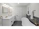 Bright bathroom featuring double sinks, stylish mirrors, a freestanding tub and sleek fixtures at 11035 W Lakeshore Dr, Carmel, IN 46033
