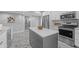 Bright kitchen offers stainless appliances, white cabinets, granite countertops, and a gray kitchen island at 235 E 11Th St, Indianapolis, IN 46202