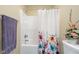 Bright bathroom features a tub with a colorful floral shower curtain and purple towel at 6045 Channel Dr, Columbus, IN 47201