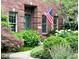 Inviting brick home featuring a well-manicured front yard, lush greenery, and an American flag at 6045 Channel Dr, Columbus, IN 47201