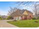 Brick exterior elevation features a well-kept lawn, mature trees, and a spacious driveway leading to a three-car garage at 6045 Channel Dr, Columbus, IN 47201
