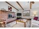Welcoming living room featuring a brick fireplace, wood floors, beamed ceiling, and lots of natural light at 7326 Caboose Ct, Indianapolis, IN 46256