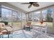 Well-lit sunroom with neutral colors, featuring views of the backyard, a ceiling fan, and a cozy seating area at 7326 Caboose Ct, Indianapolis, IN 46256