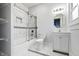 Bright bathroom featuring marble-look tile, new vanity, shower and tub combo, and large window at 832 N Parker Ave, Indianapolis, IN 46201