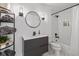 Modern bathroom with subway tiled shower/tub, dark vanity, round mirror and black hardware at 9046 Pinecreek Ct, Indianapolis, IN 46256