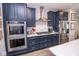 Modern kitchen featuring stainless steel appliances, cooktop, double ovens, and elegant dark blue cabinetry at 9748 Junction Station, Fishers, IN 46037